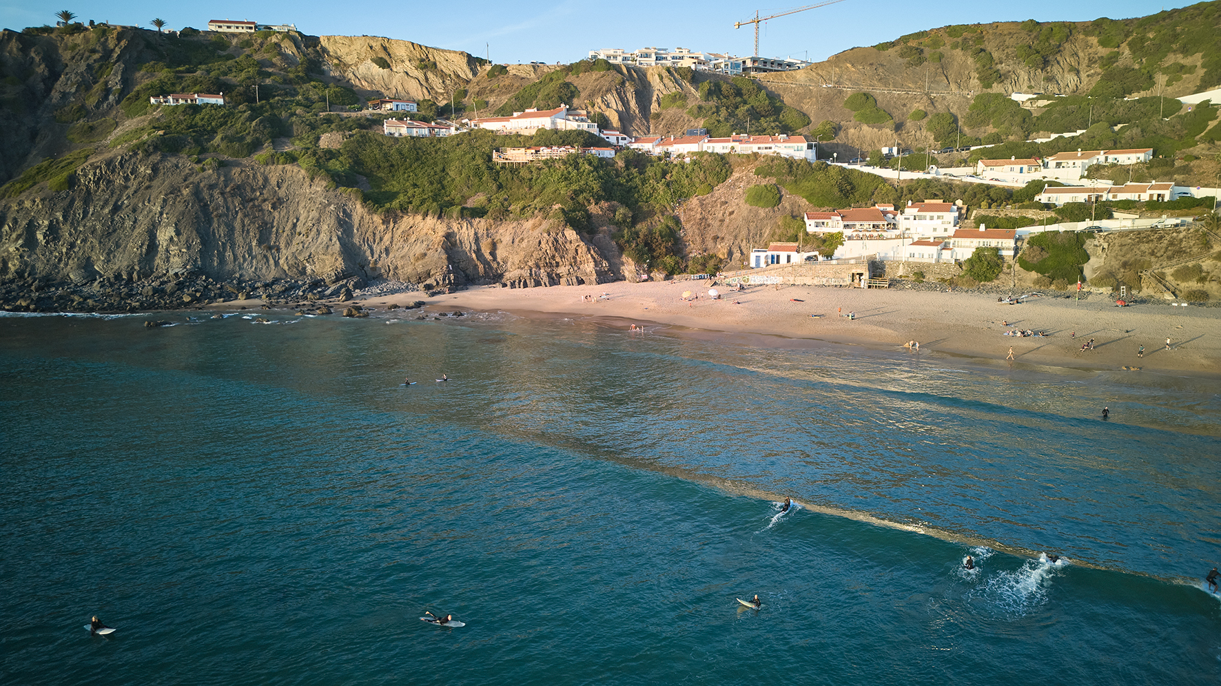 View from the sea towards Arrifana, with surfers enjoying the waves, highlighting how the ‘Do Nothing’ practice balances human recreation with the preservation of natural coastal dynamics. Photo Nuno Cera, 2025.