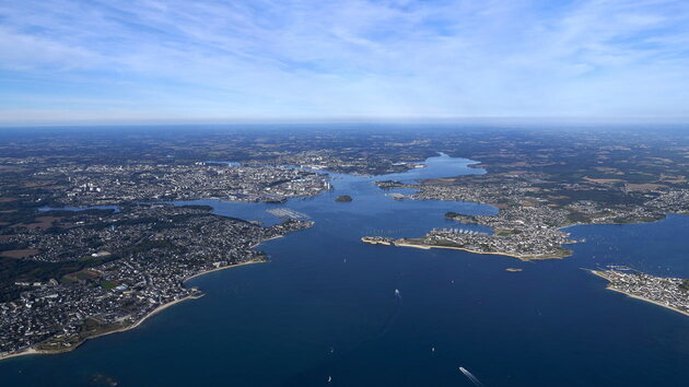 Layered maritime landscape combining ports, naval infrastructure and circulation routes within a semi-enclosed coastal system.